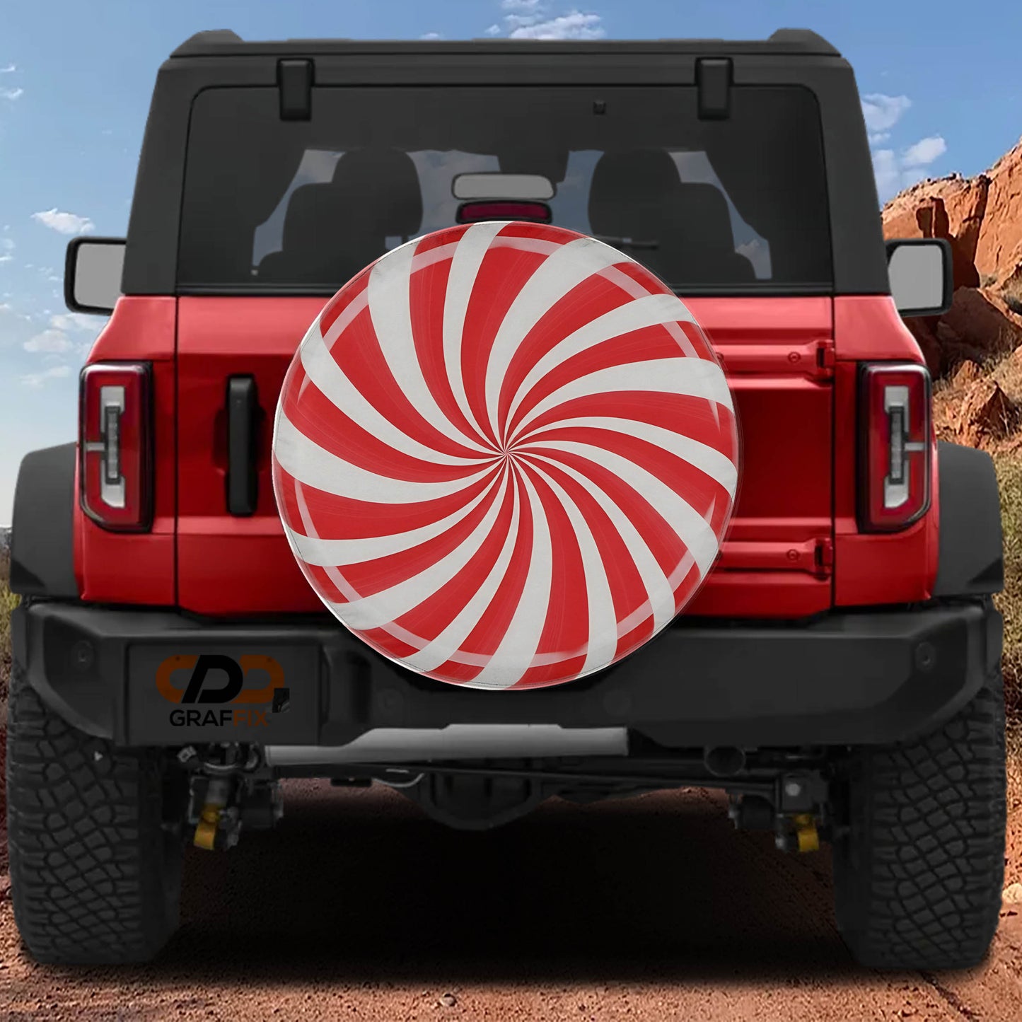 A red Jeep Wrangler with a large white and red spiral-patterned spare tire attached to the rear.