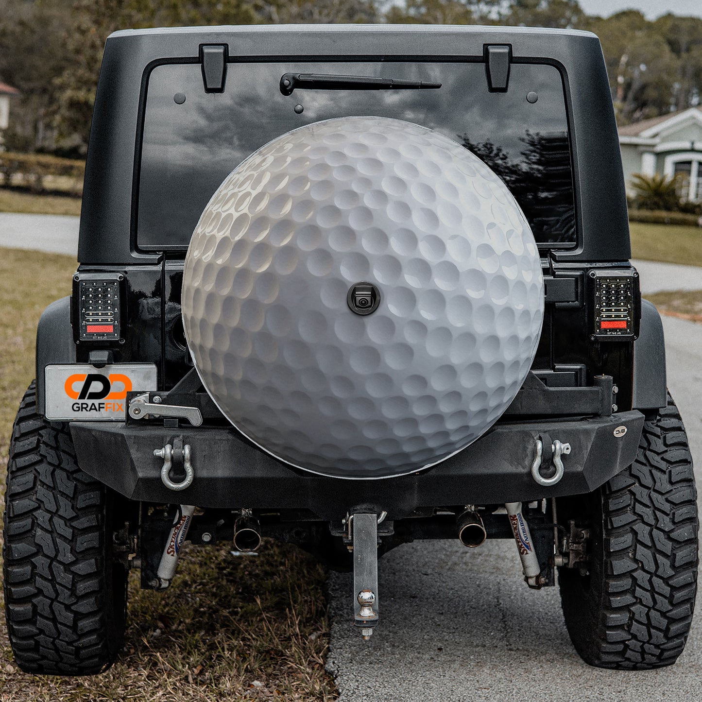 a black Jeep Wrangler with a large silver golf ball mounted on the rear bumper.