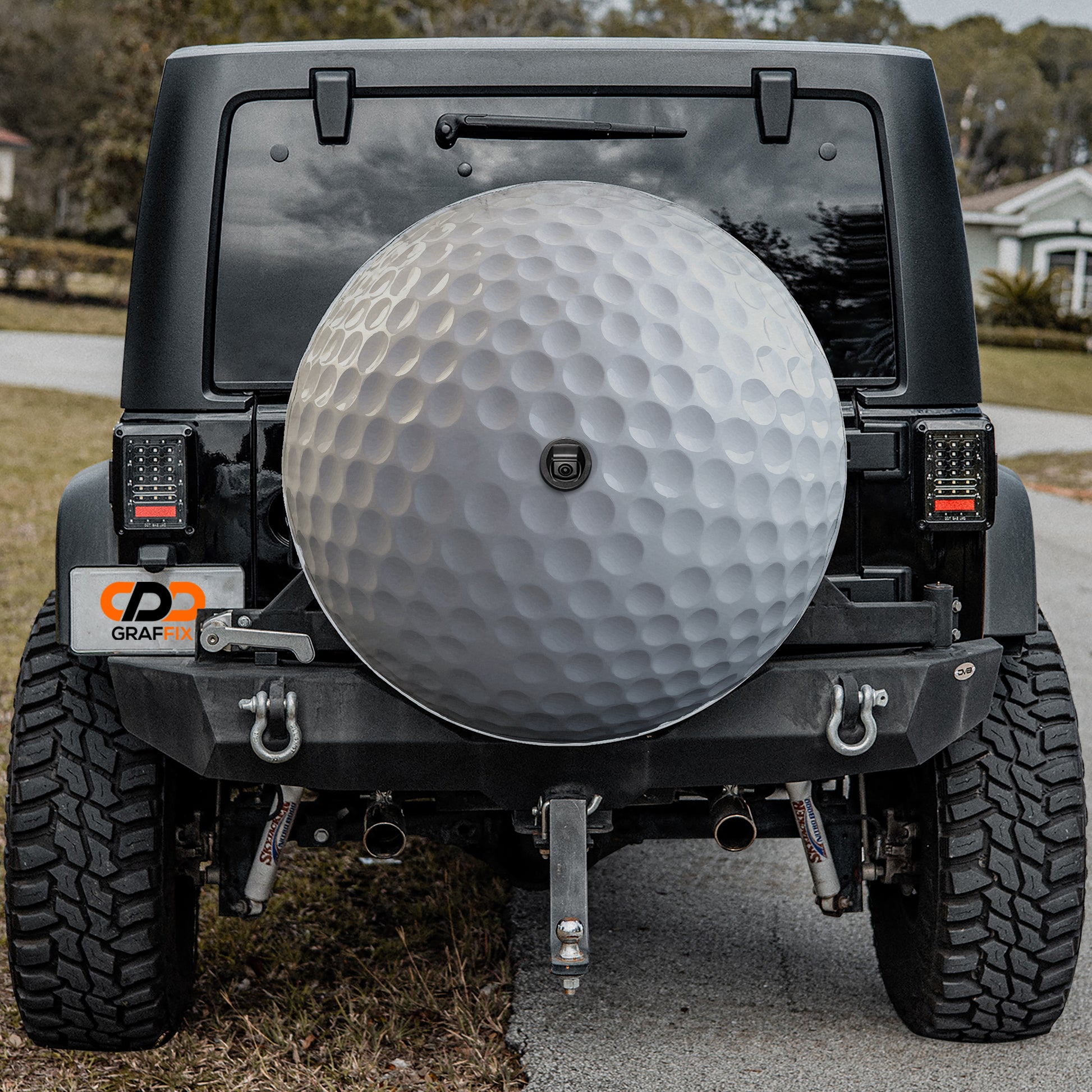 a black Jeep Wrangler with a large silver golf ball mounted on the rear bumper.