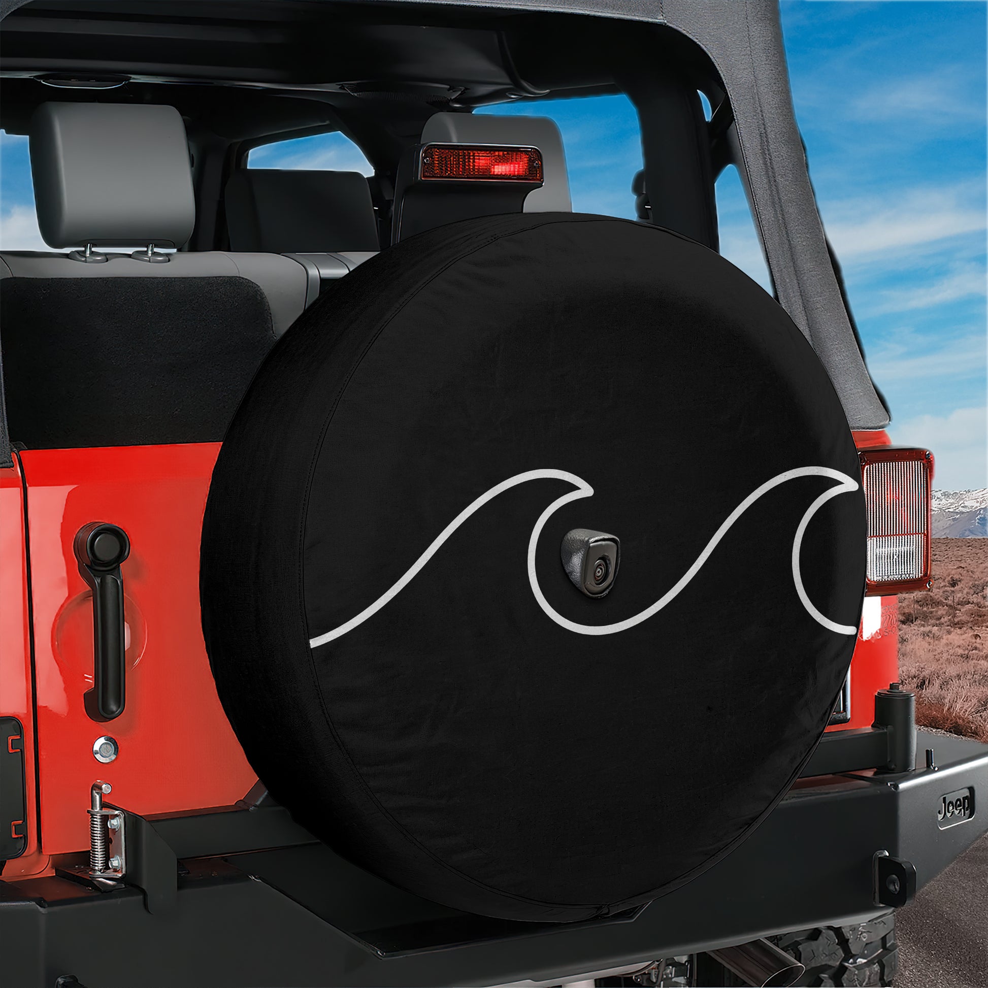 A red Jeep Wrangler with a black tire cover featuring a wave design, parked in a desert-like environment.