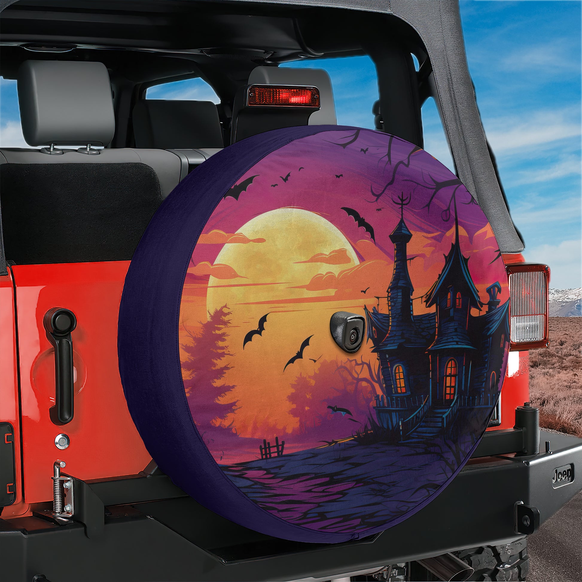 A spooky Halloween-themed wheel cover is attached to the rear of a red Jeep, depicting a castle at night with bats flying around it.