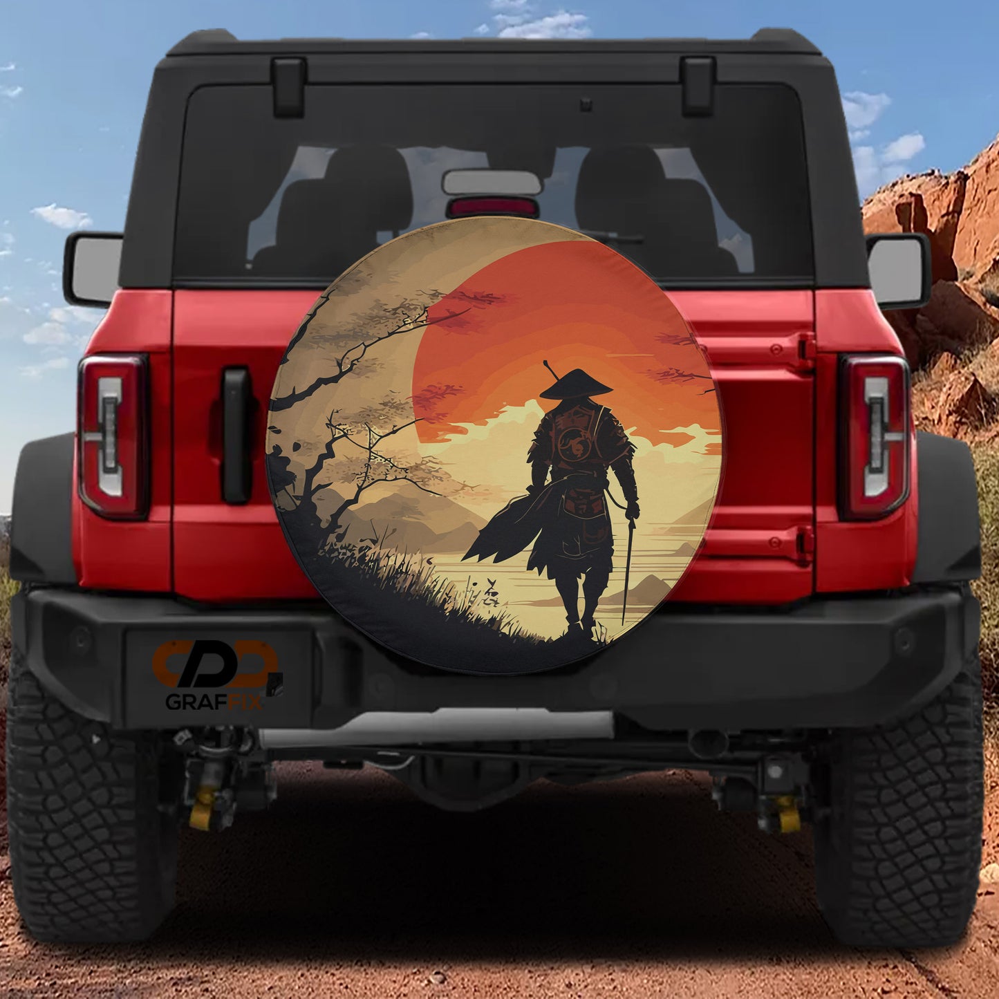 A red Jeep Wrangler with a large, circular spare tire cover featuring a Japanese-style warrior silhouette against a sunset landscape.