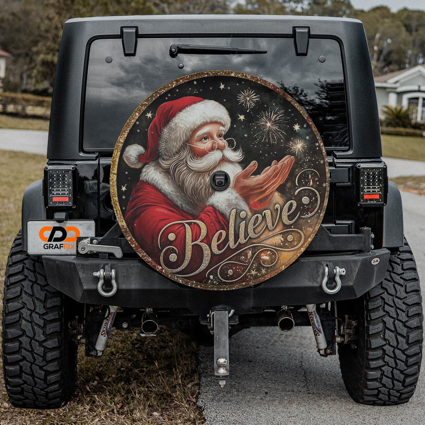 a black Jeep Wrangler with a large, round, and decorative wheel cover featuring a Santa Claus image and the word "Believe" written on it.