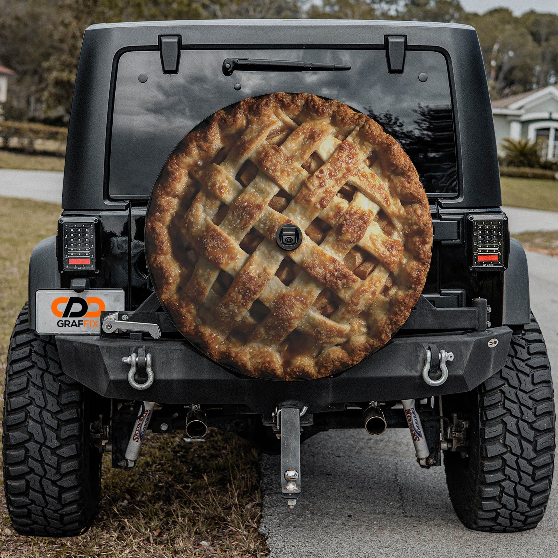a black Jeep Wrangler with a pie-shaped cover on the rear window, which appears to be a custom design or decoration.