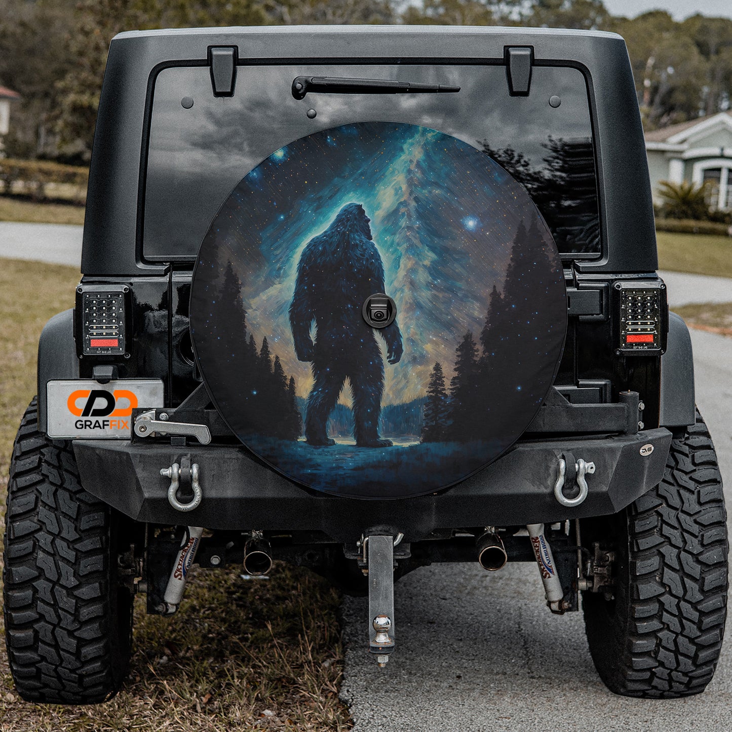 a large, round, black tire cover with a picture of a giant, unidentified creature on it, which appears to be a Sasquatch or similar mythical creature.