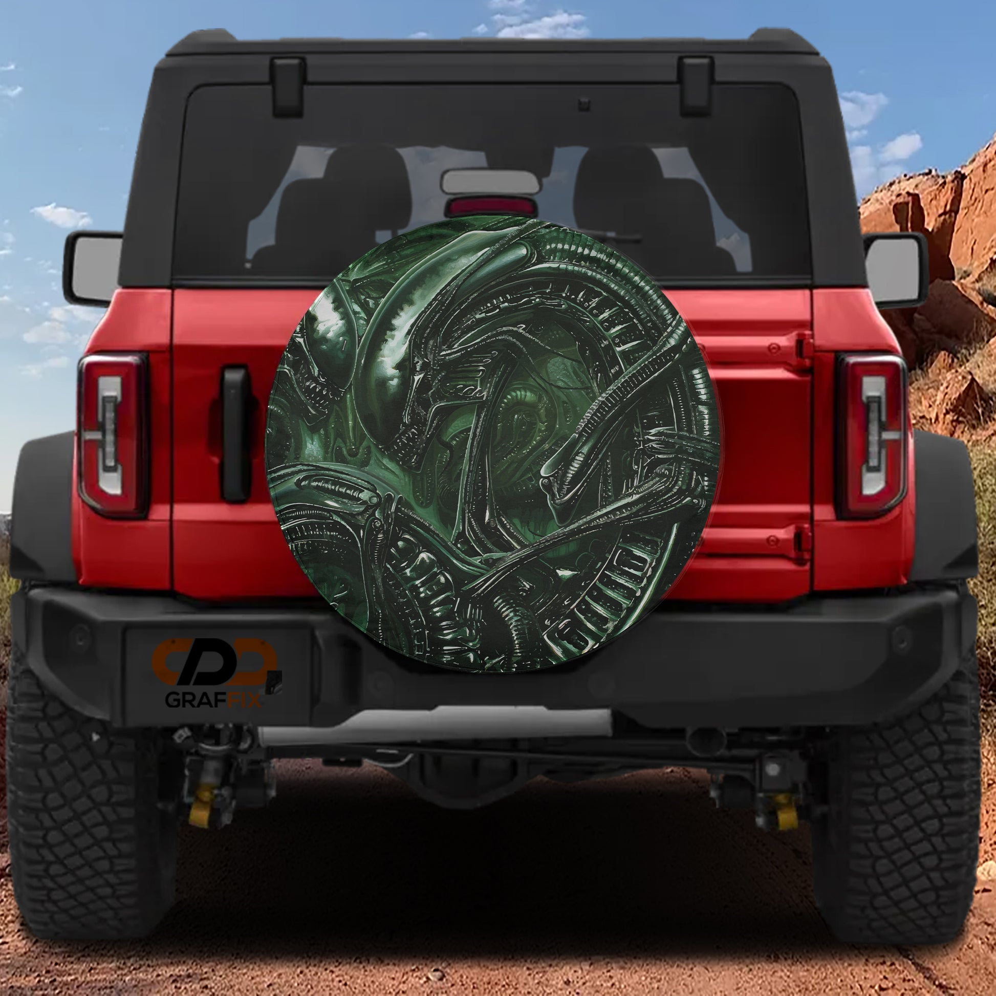 the rear of a red Jeep Wrangler with a large green alien-like design on the rear window.