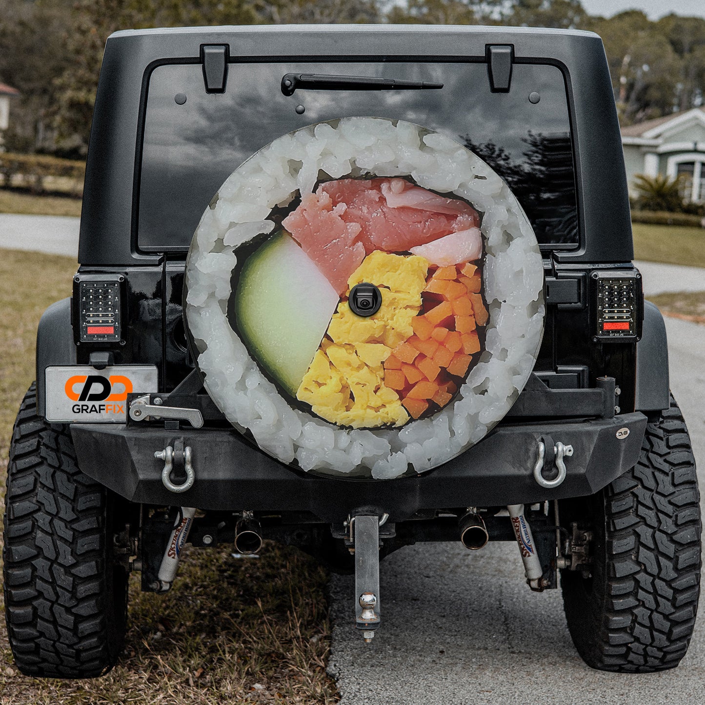 a black Jeep Wrangler with a large, colorful wheel cover on the rear of the vehicle.