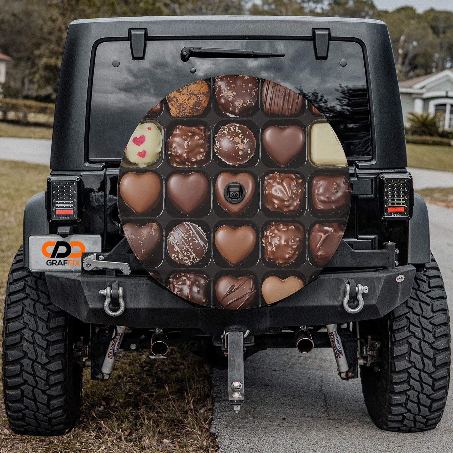 a black Jeep Wrangler with a large chocolate-themed spare tire cover attached to the rear of the vehicle.