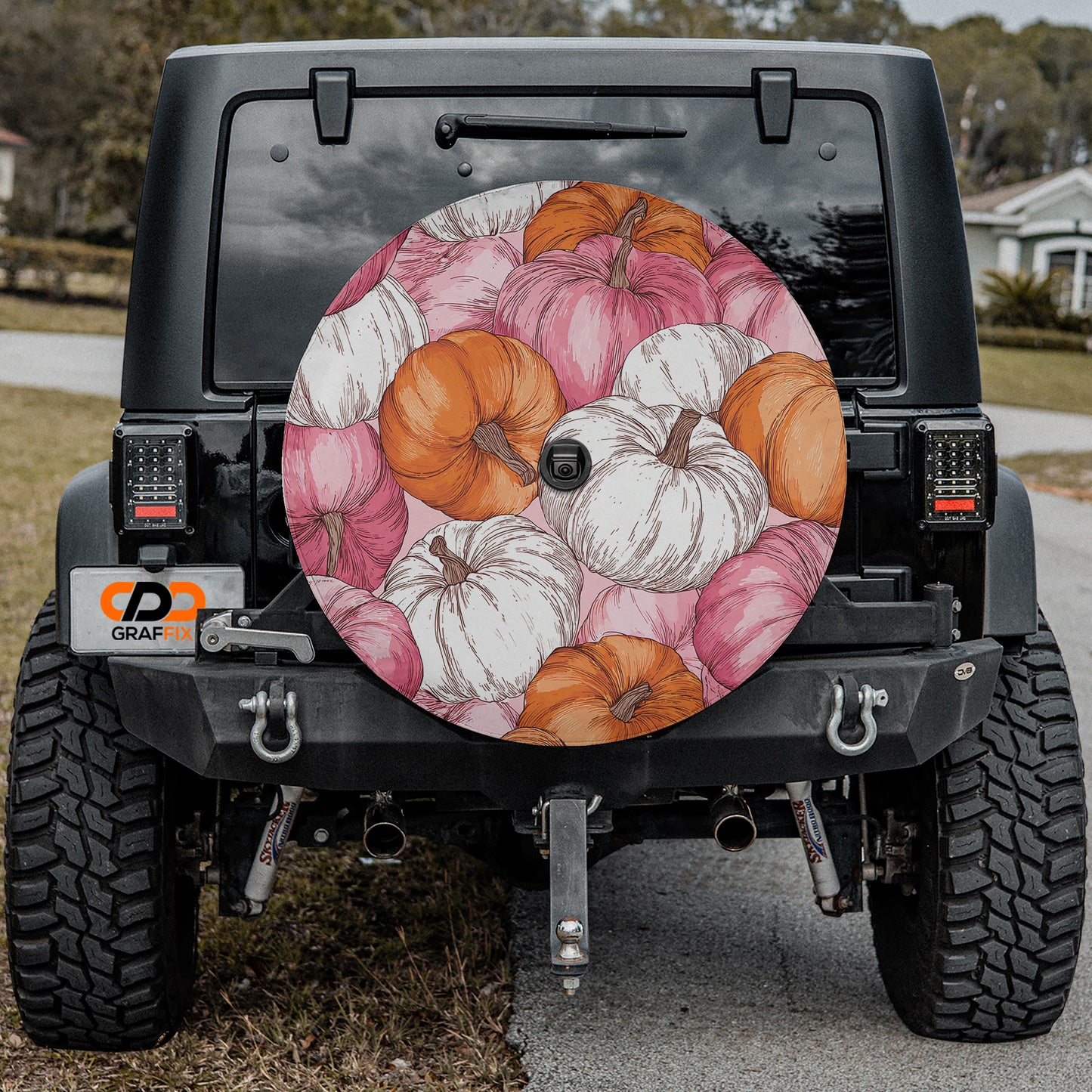 the back of a black Jeep Wrangler with a large, colorful wheel cover featuring a pumpkin design.