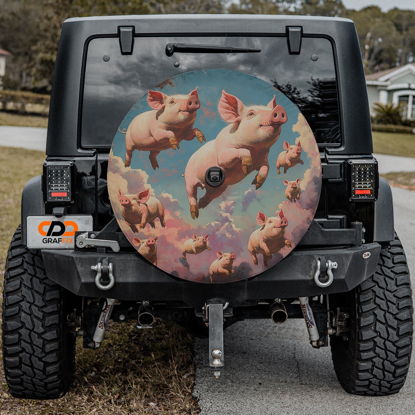 a black Jeep Wrangler with a large rear wheel cover depicting a whimsical scene of pigs flying through a cloudy sky.