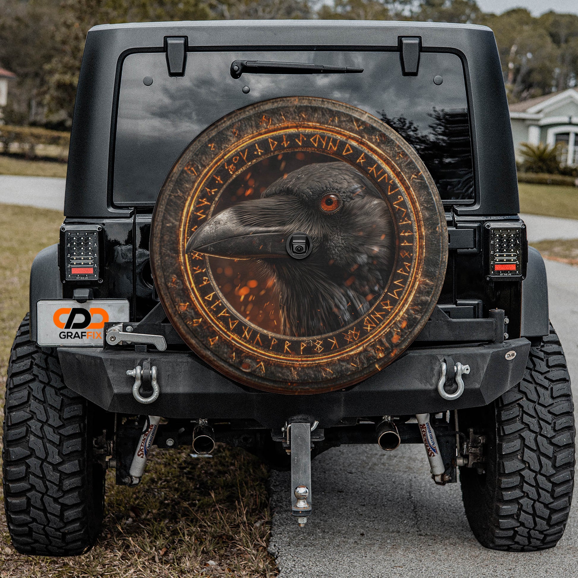 the rear of a black Jeep Wrangler with a large, decorative wheel cover featuring a bird's head.