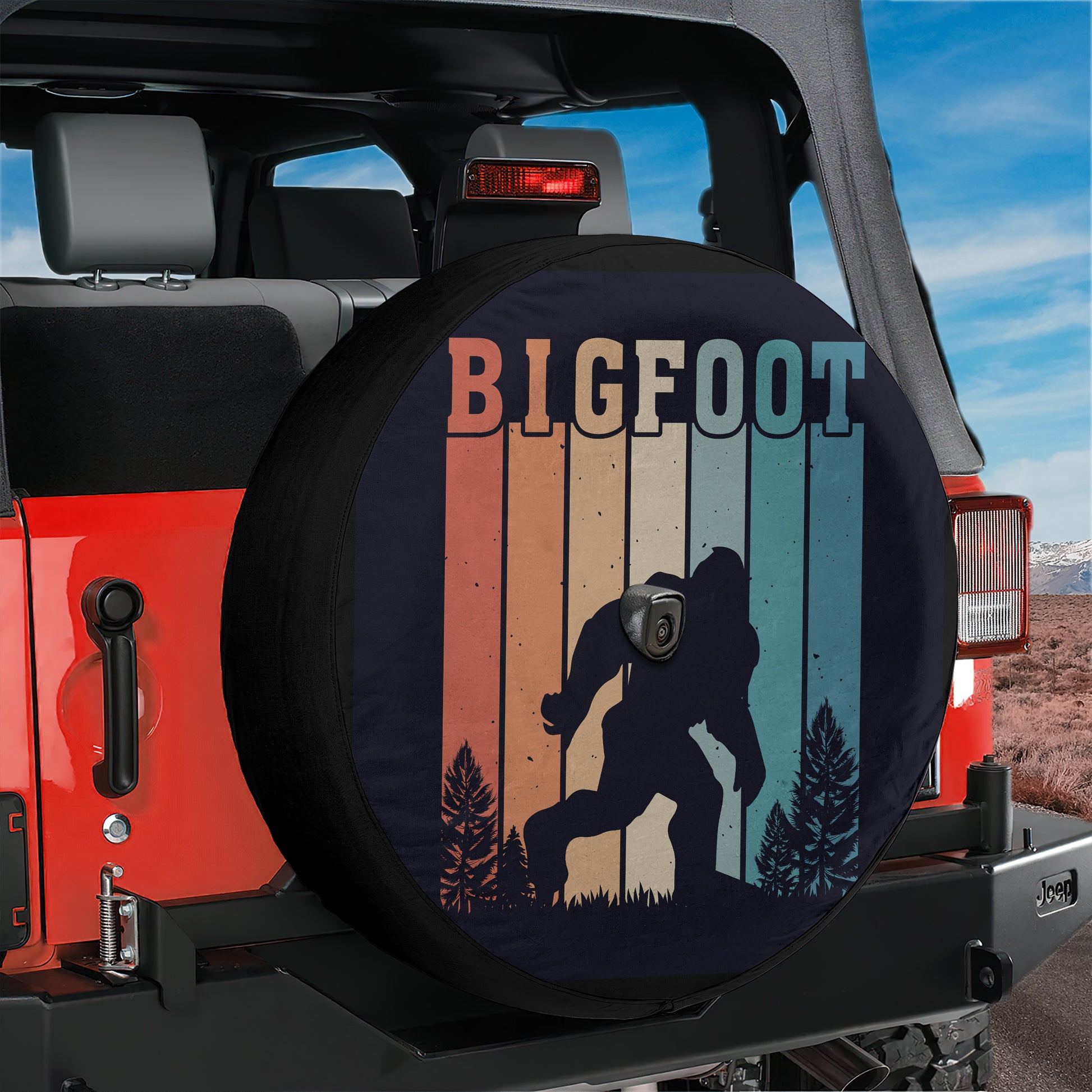 A red Jeep with a tire cover featuring a silhouette of a Sasquatch, a mythical creature from the American West, and a gradient background.