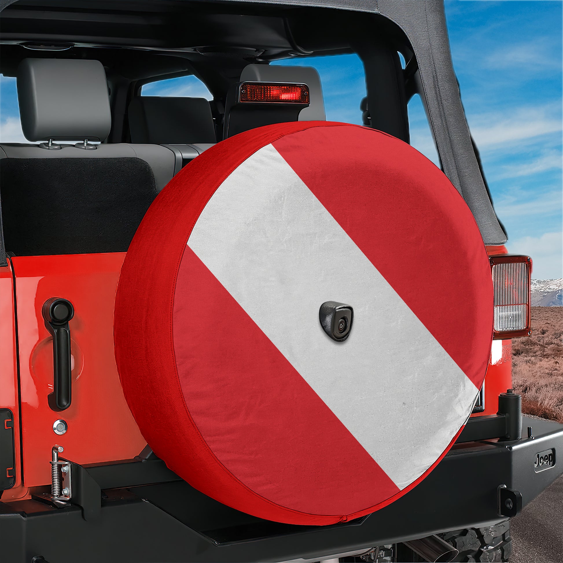 A red and white spare tire cover is attached to the rear of a Jeep vehicle, with a desert landscape visible in the background.