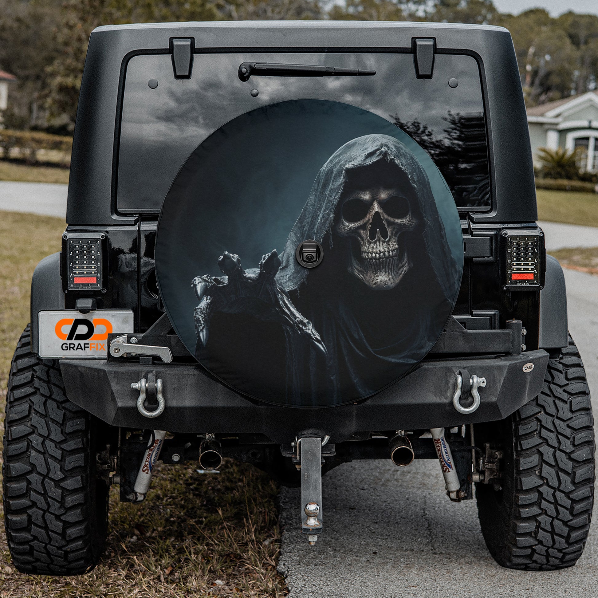 a black Jeep Wrangler with a skull-themed spare tire cover on the rear.