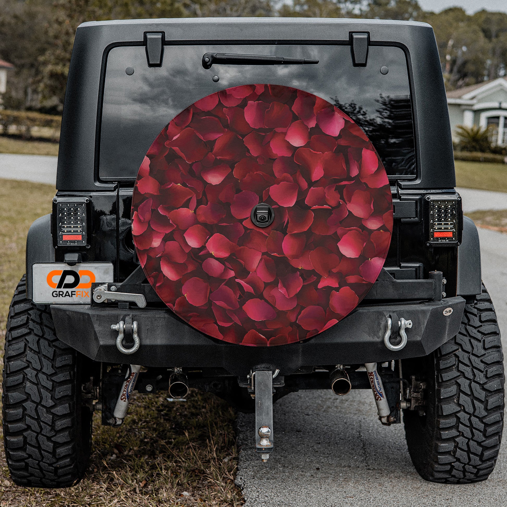 the rear of a black Jeep Wrangler with a large, round, rose-colored wheel cover attached to the vehicle.