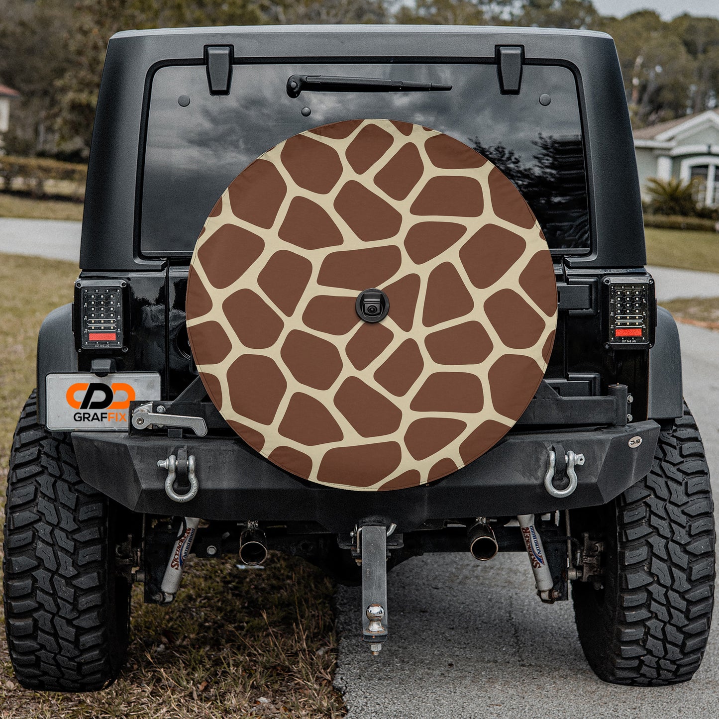 the rear of a black Jeep Wrangler with a large giraffe-patterned spare tire attached to the vehicle.