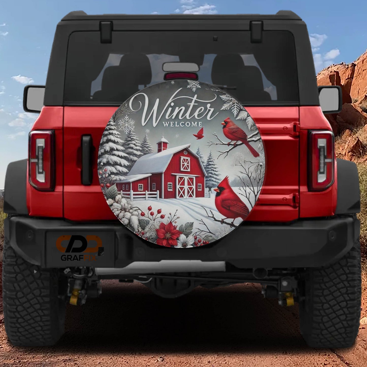A red Jeep Wrangler with a winter-themed spare tire cover featuring a red barn, snow, and red birds.