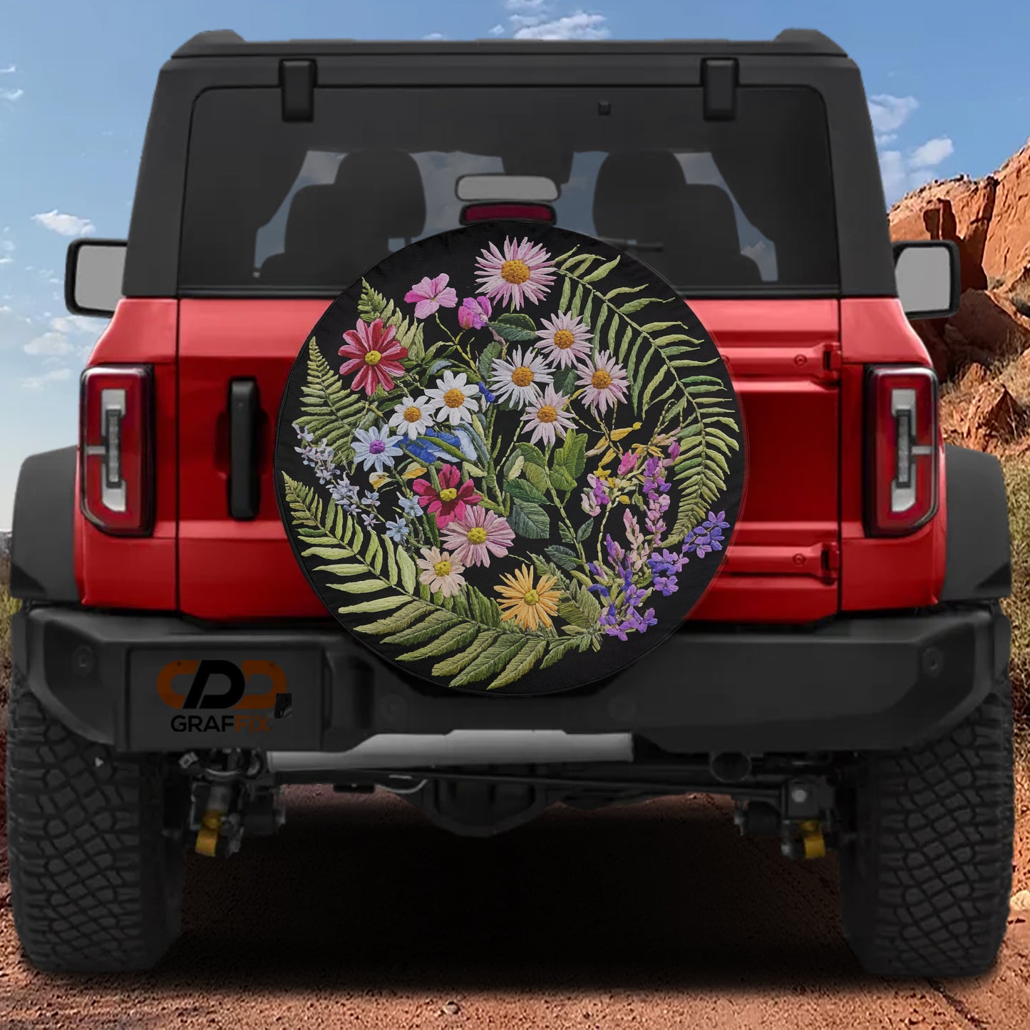 A red Jeep Wrangler with a large floral wheel cover attached to the rear of the vehicle.
