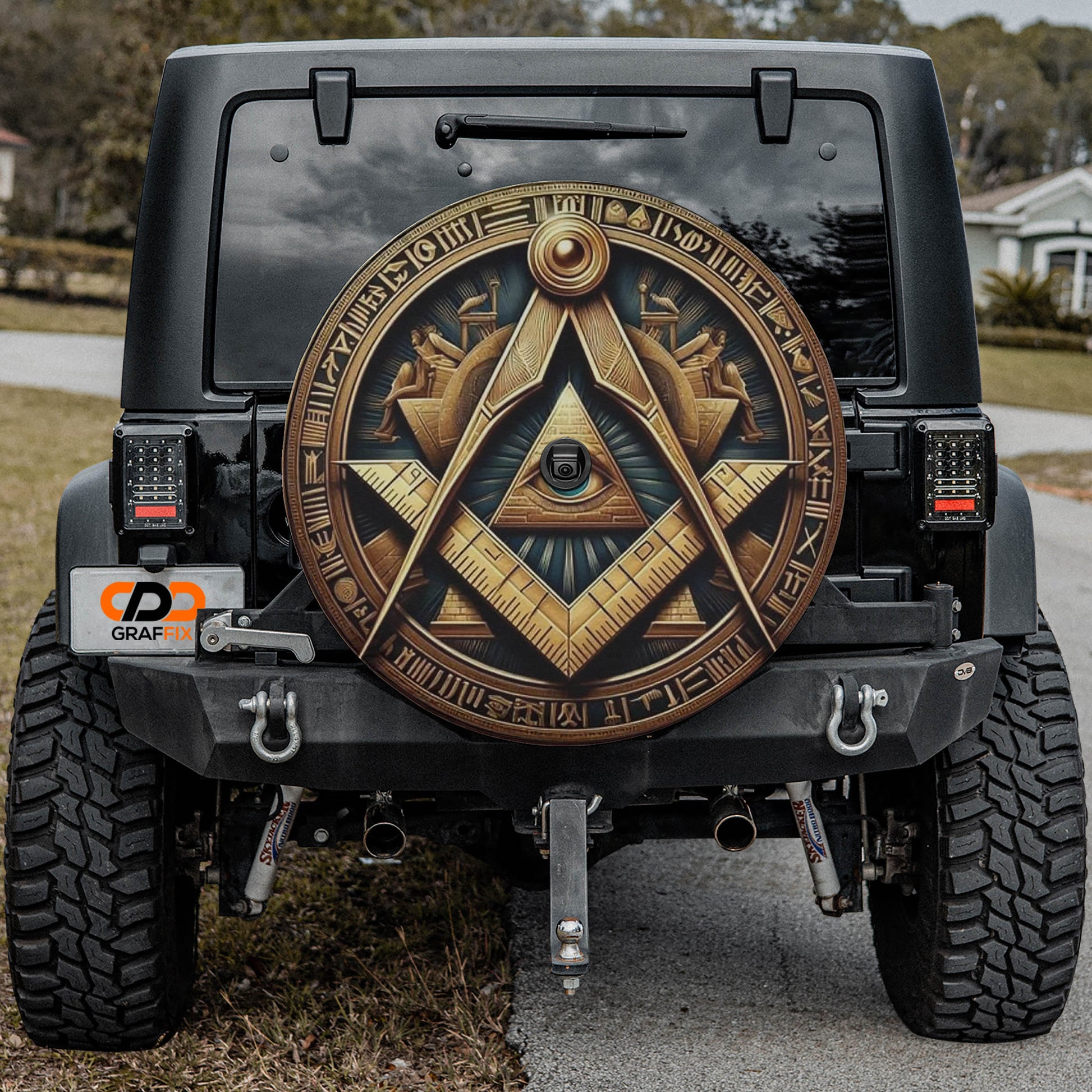 the back of a black Jeep Wrangler with a large, ornate wheel cover featuring an Egyptian-inspired design.