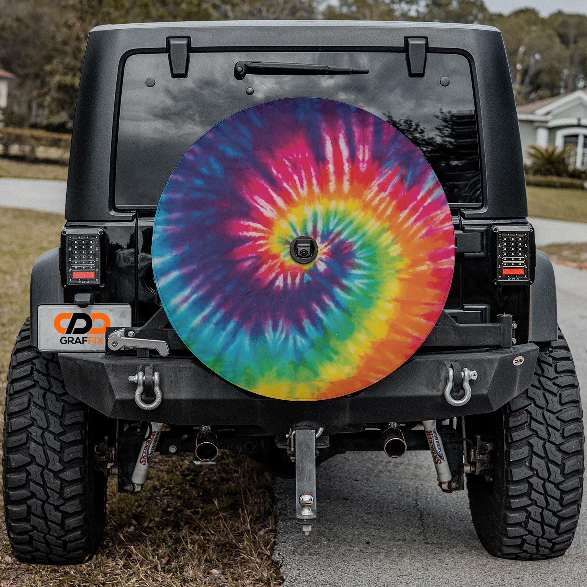 a colorful tie - dyed wheel cover on the back of a jeep