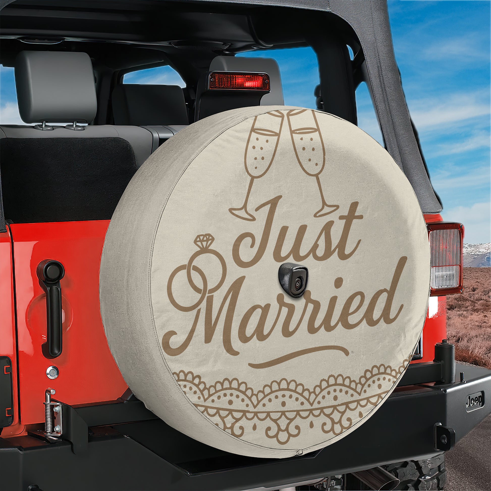 A spare tire cover with the text "Just Married" printed on it, placed on the back of a red Jeep.