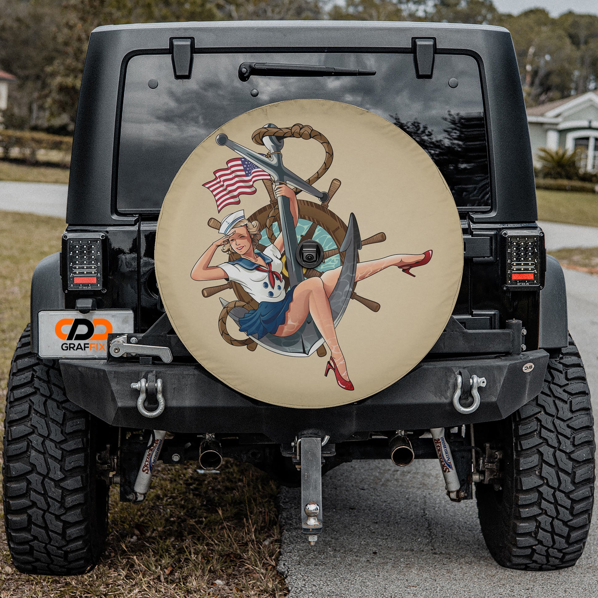 a black Jeep Wrangler with a large, round spare tire cover featuring a nautical theme, including a woman in a sailor's outfit and an anchor.