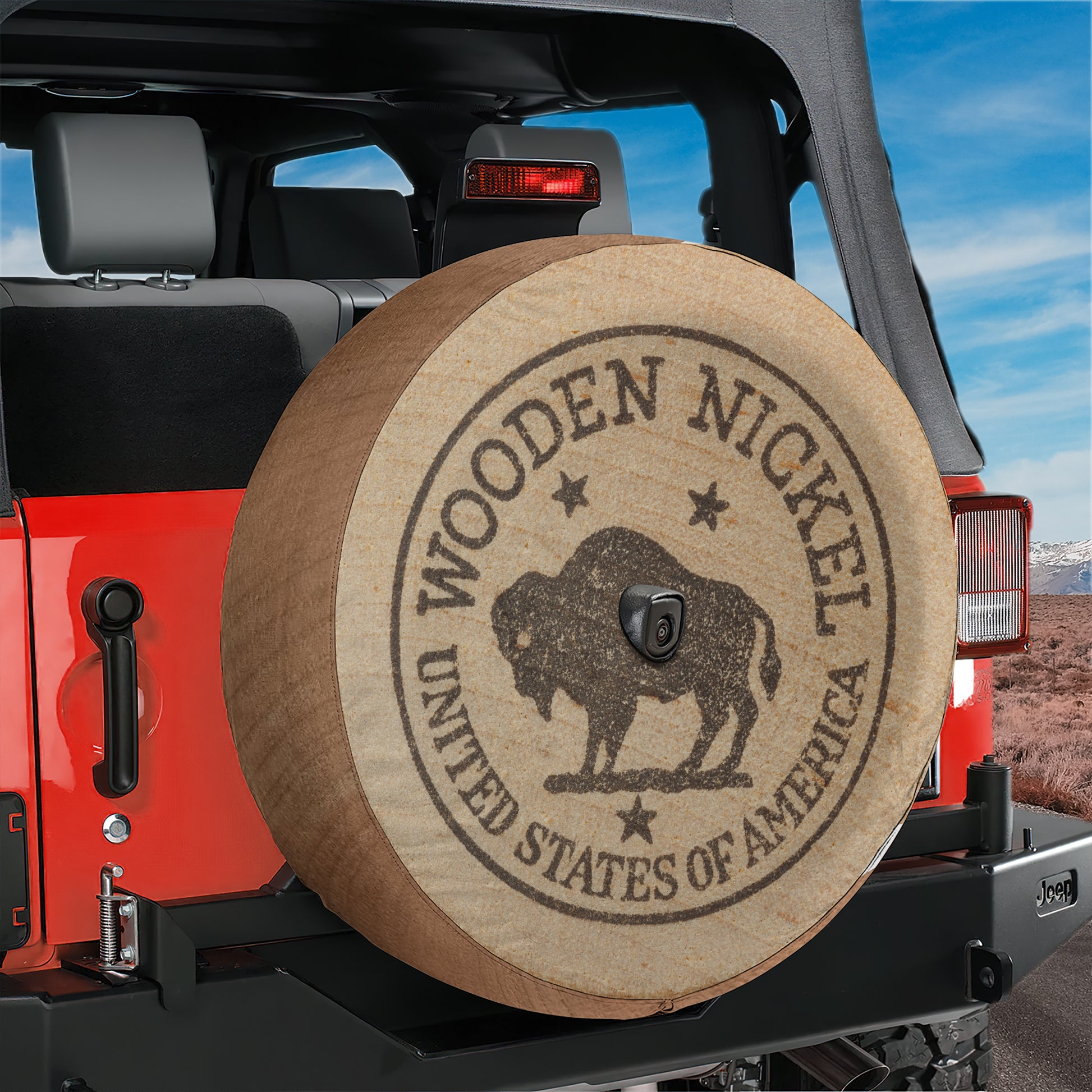 A red Jeep Wrangler with a wooden spare tire attached, featuring a circular emblem with the text "WOODEN NICKEL" and "UNITED STATES OF AMERICA".