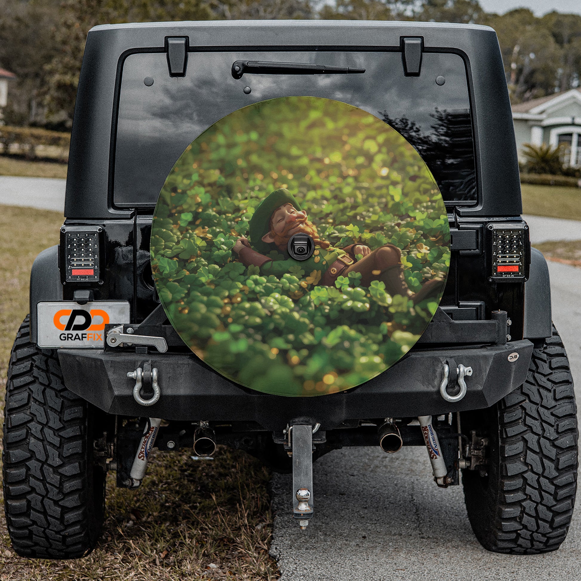 a black Jeep Wrangler with a large, circular spare tire cover on the rear window, featuring a person lying in a field of flowers.