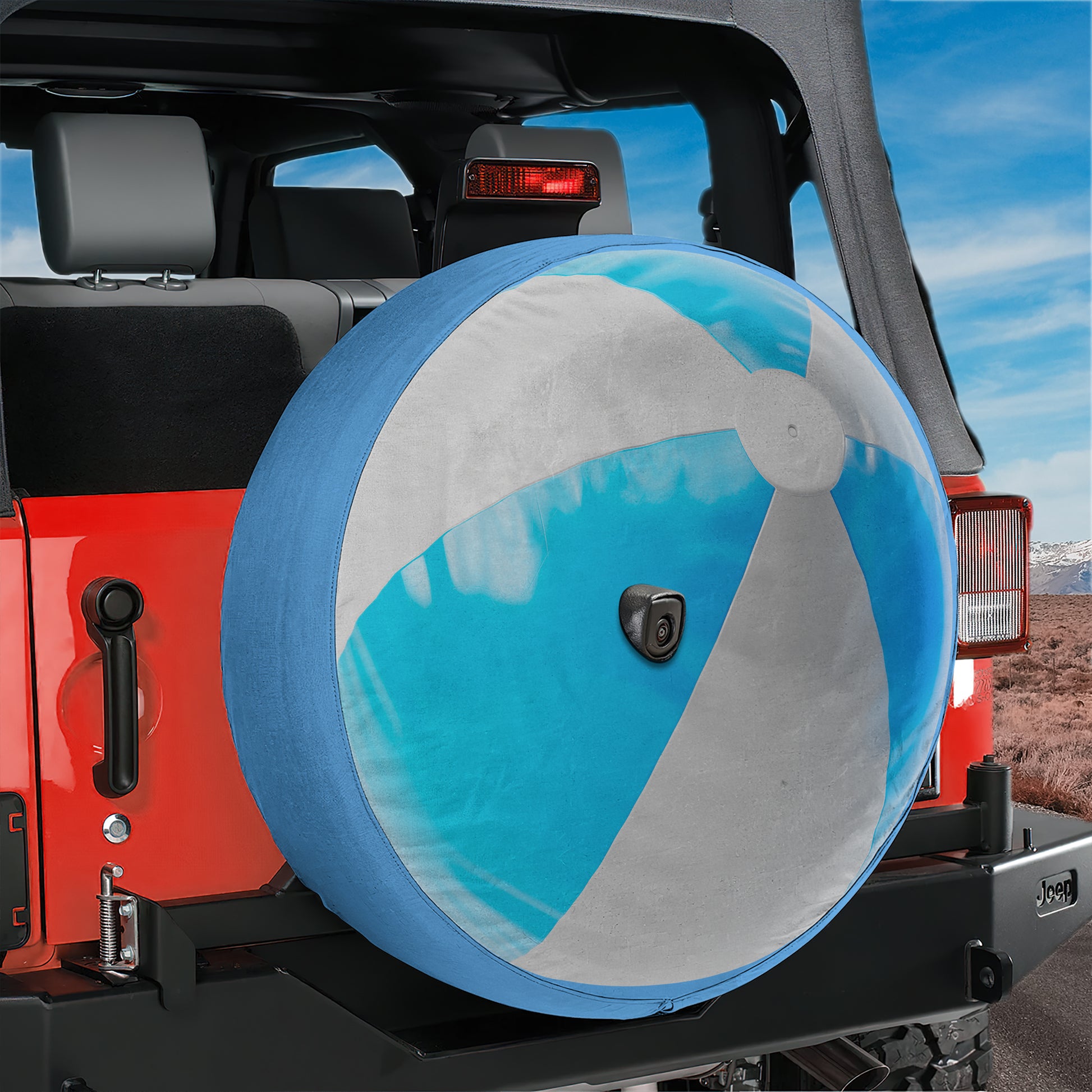 A red Jeep with a large inflatable beach ball attached to the rear tire.