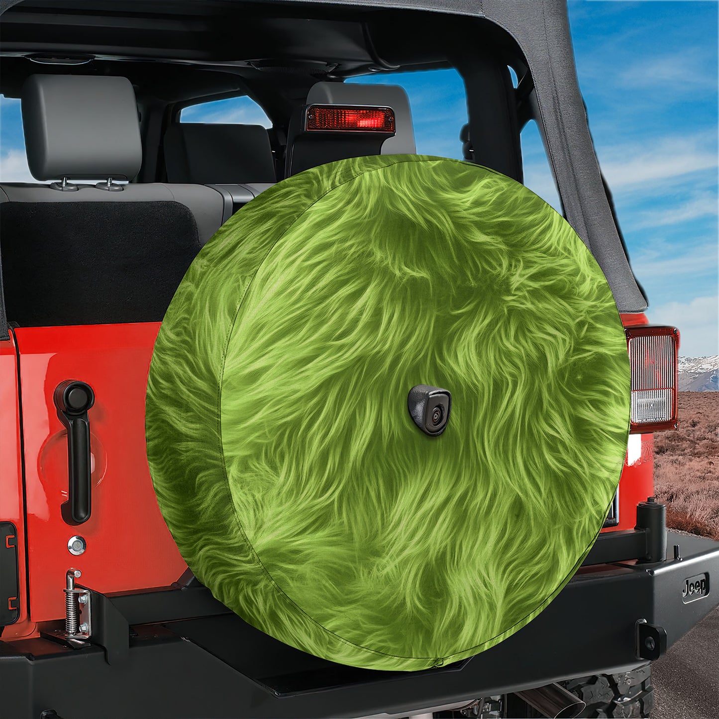 A red Jeep Wrangler with a large, fuzzy green tire cover attached to the rear of the vehicle.