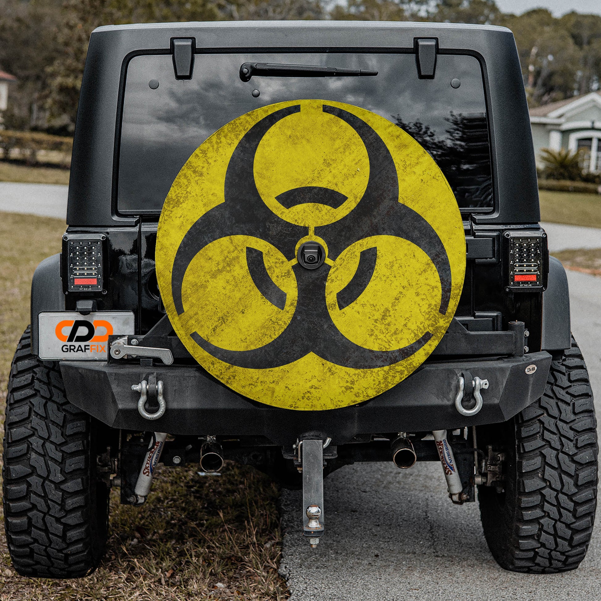 a black Jeep Wrangler with a large, yellow biohazard symbol on the rear window.