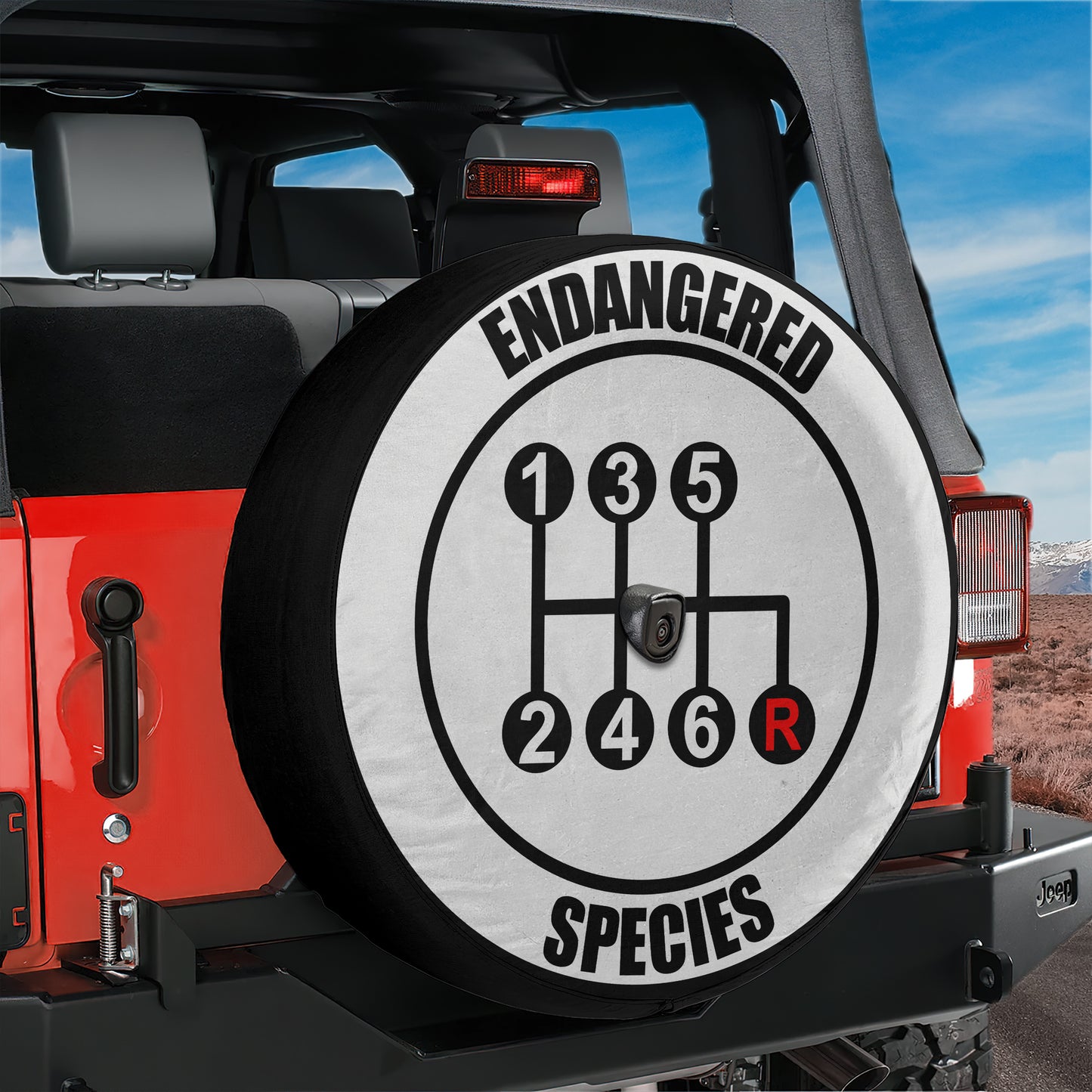 A spare tire cover with the text "ENANGERED SPECIES" printed on it, which is mounted on the rear of a red Jeep.