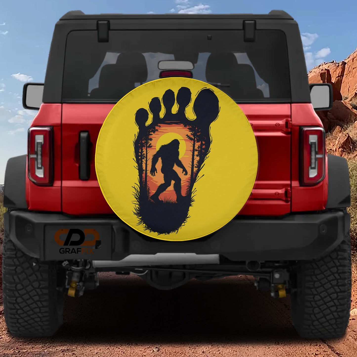 a red Jeep Wrangler with a large tire cover featuring a silhouette of a Sasquatch.