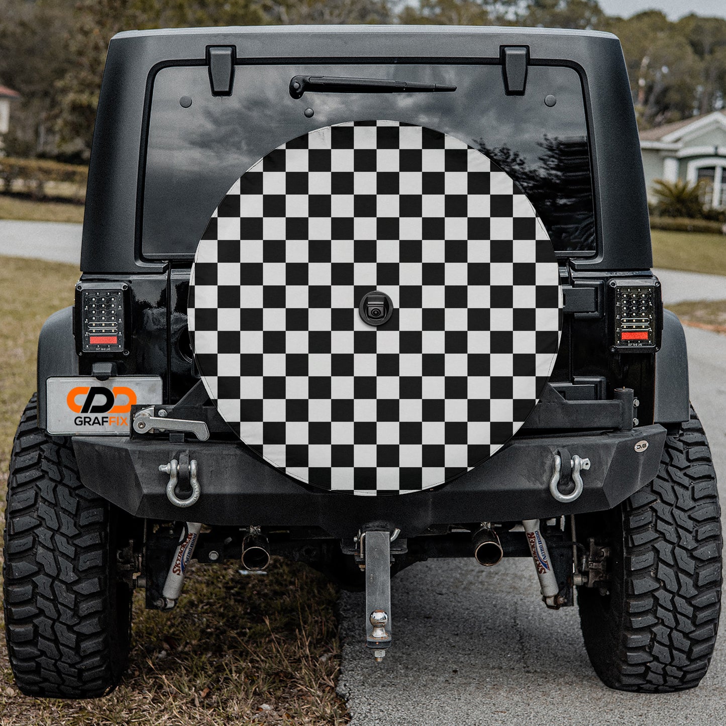 a black Jeep Wrangler with a checkered wheel cover on the rear of the vehicle.