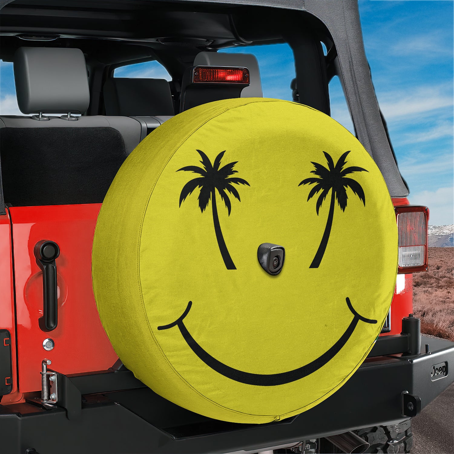 A yellow tire cover with a smiley face design is attached to the rear of a red Jeep vehicle.