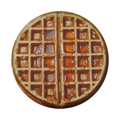 A waffle with syrup dripping from it, presented in a circular shape.