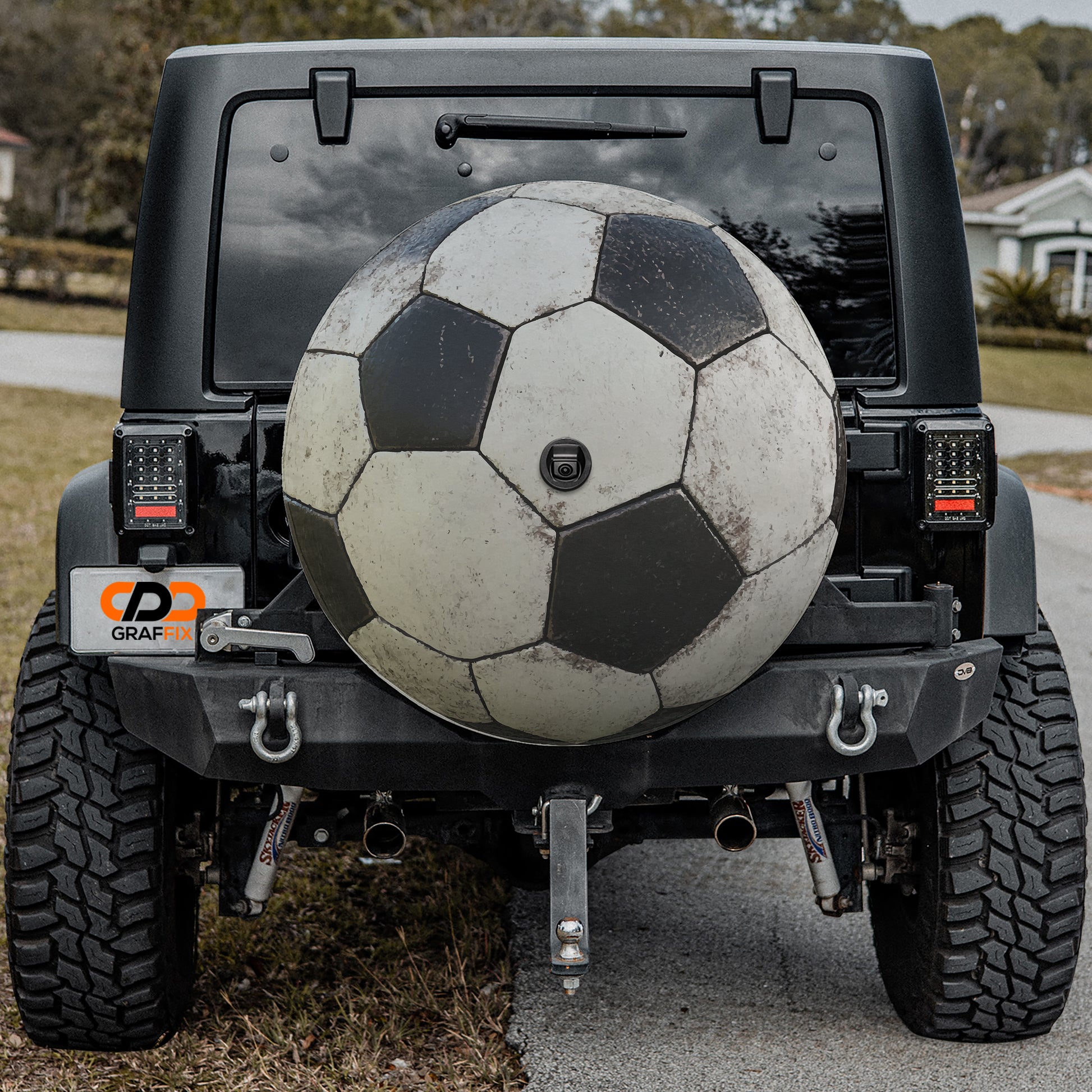 A black Jeep Wrangler with a large soccer ball mounted on the rear bumper.