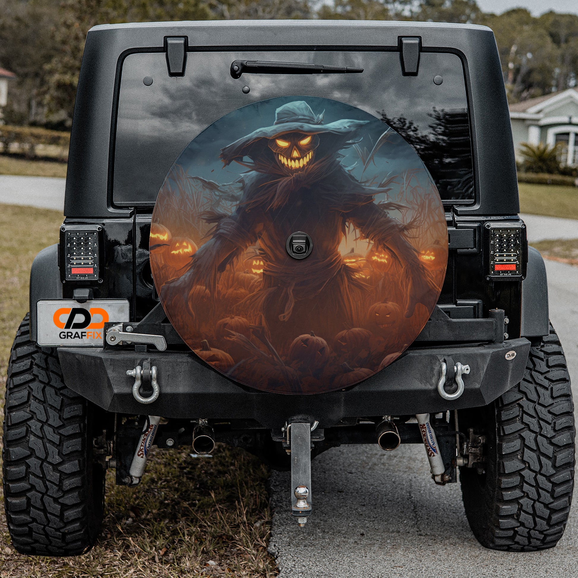 a large, spooky-looking wheel cover with a creepy-looking character on it, mounted on the back of a black vehicle.