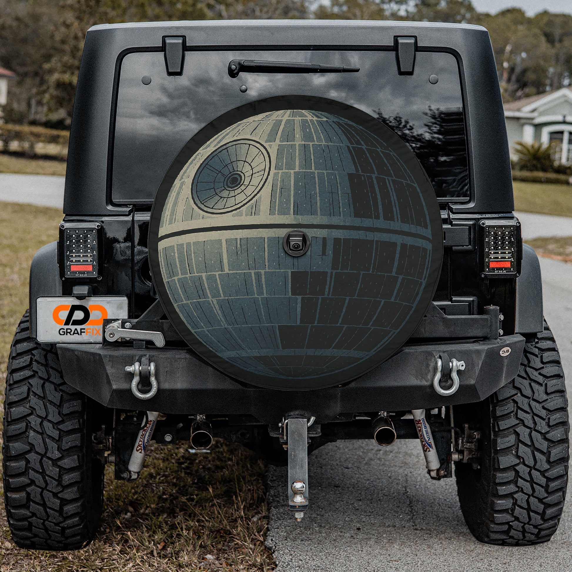 a black Jeep Wrangler with a large, round, space-themed spare tire attached to the rear of the vehicle.