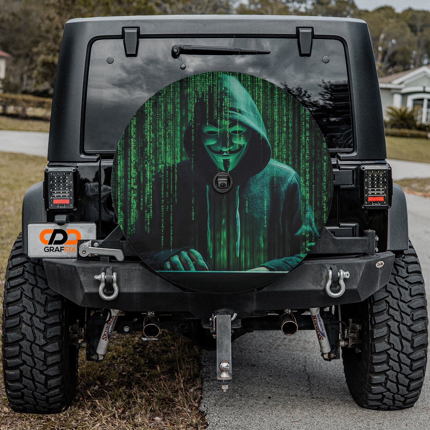 a black Jeep Wrangler with a large wheel cover featuring a hooded figure with a mask and a green background.