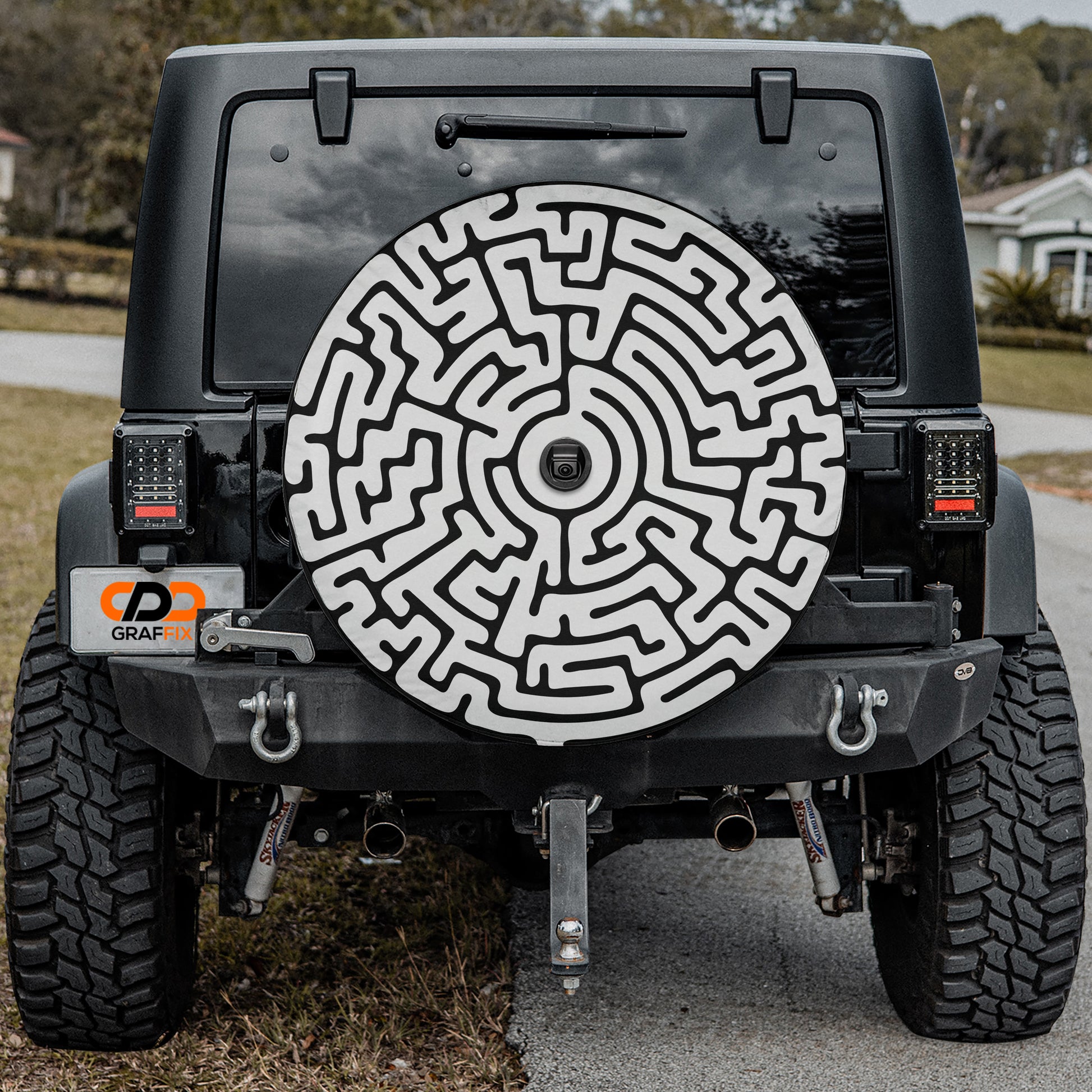 the back of a black Jeep Wrangler with a large, intricate maze-like design on the rear window.