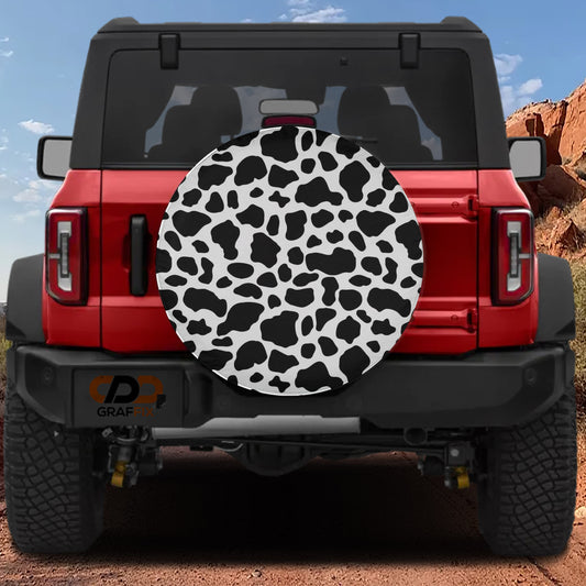 the rear view of a red Jeep Wrangler with a cow print spare tire attached to it.