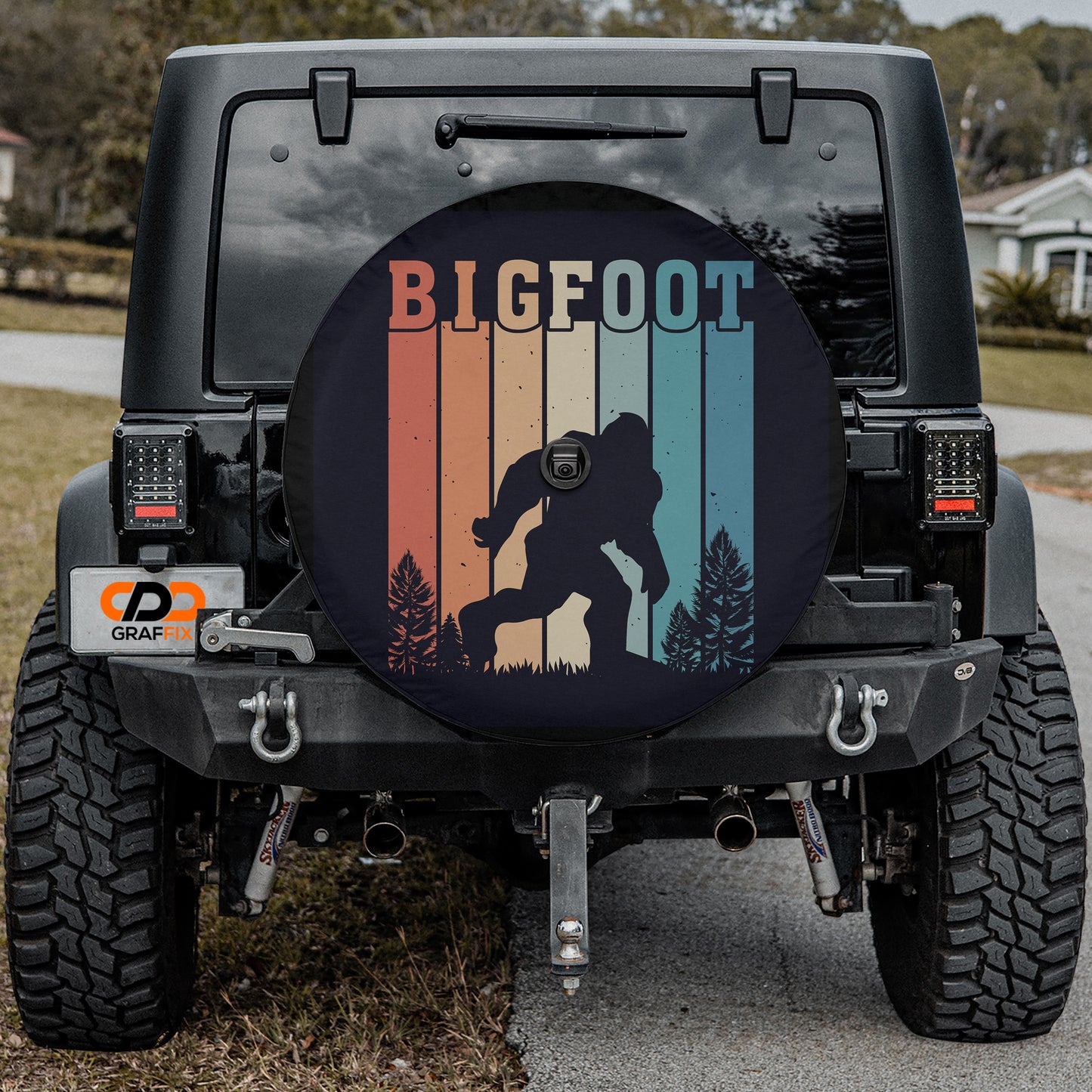 the back of a black Jeep Wrangler with a large tire cover featuring a silhouette of a Sasquatch.